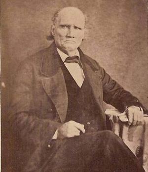Sepia portrait photograph of Morgan Walker, and elderly man, seated with a coat and tie
