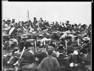 Photograph of a large crowd with Abraham Lincoln visible, delivering a speech